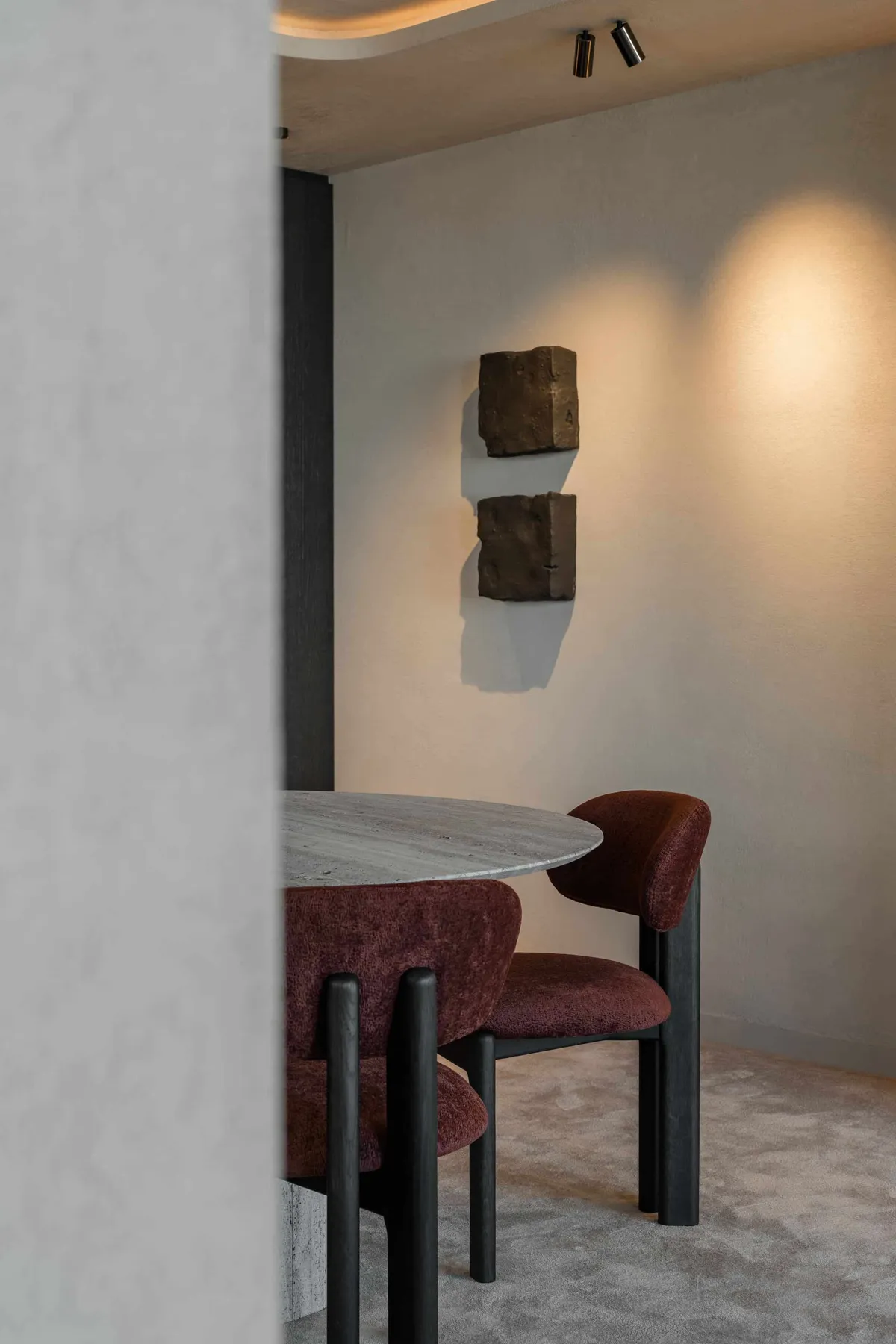 Eetkamer met travertijn tafel en bordeauxrode stoelen in het kantoor van Robi in Knokke